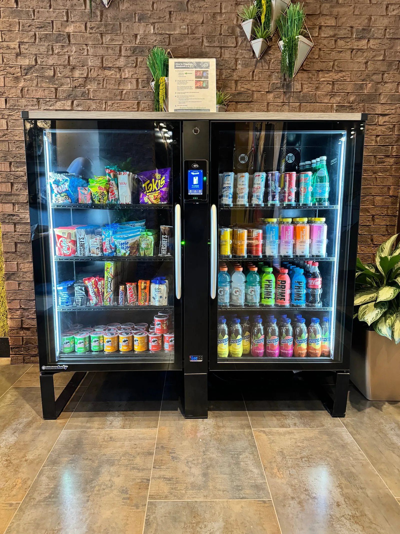 A modern, cashless Amenity Now vending machine fully stocked with premium snacks and cold beverages in a Charlotte corporate breakroom.